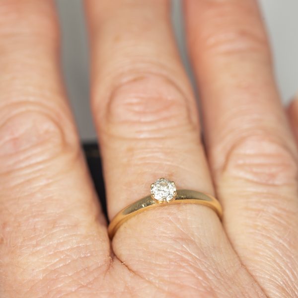 A yellow gold and diamond vintage solitaire ring worn